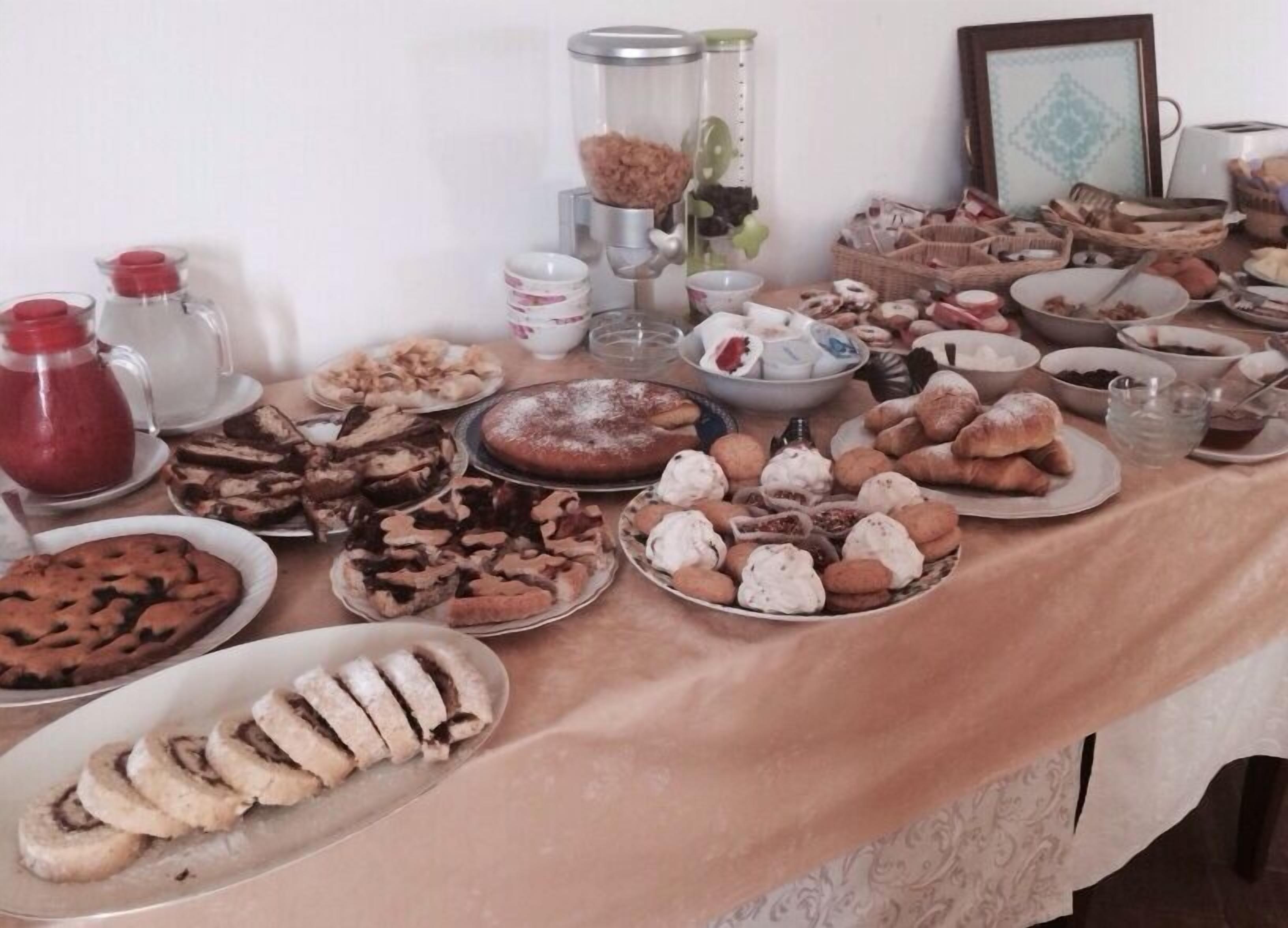 Une table sur laquelle sont disposés divers gâteaux et desserts, notamment des gâteaux, des biscuits et des pâtisseries, le tout présenté sur une nappe.