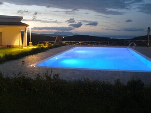 A swimming pool at dusk with a view of the mountains in the background. - Agriturismo Irghitula (Posada)