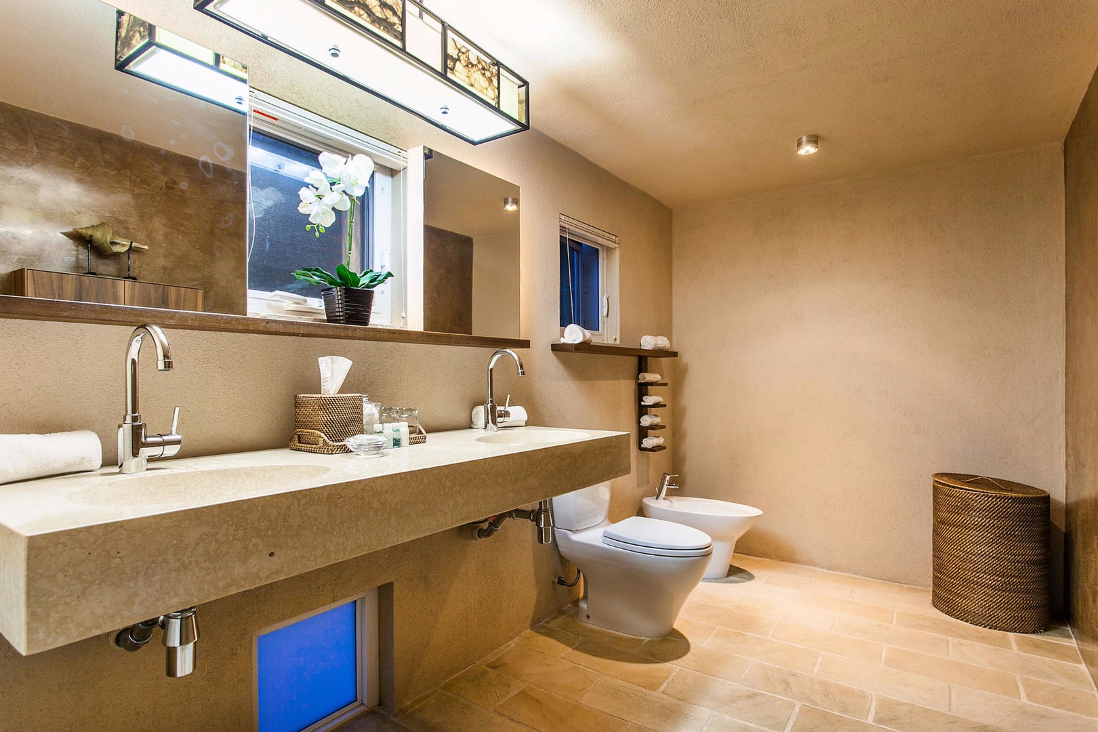 Un baño moderno con un tocador amplio, lavamanos dobles, inodoro y bidé.