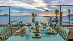 Une table dressée pour un repas, avec vue sur la mer et le coucher de soleil.