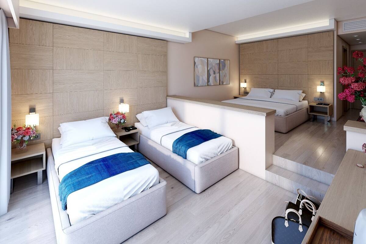 A hotel room with two beds, a small desk, and a bathroom.