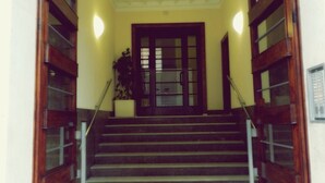 A staircase with wooden railings and a tiled floor leading to a door with glass panels. - Vatican Rome B&B (Rome)