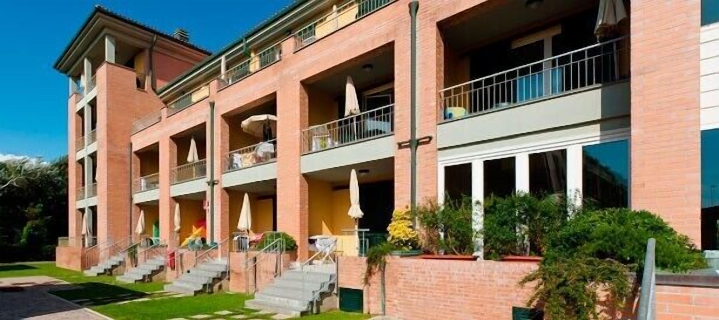 A multi-story hotel with a brick facade, balconies, and a well-maintained lawn.