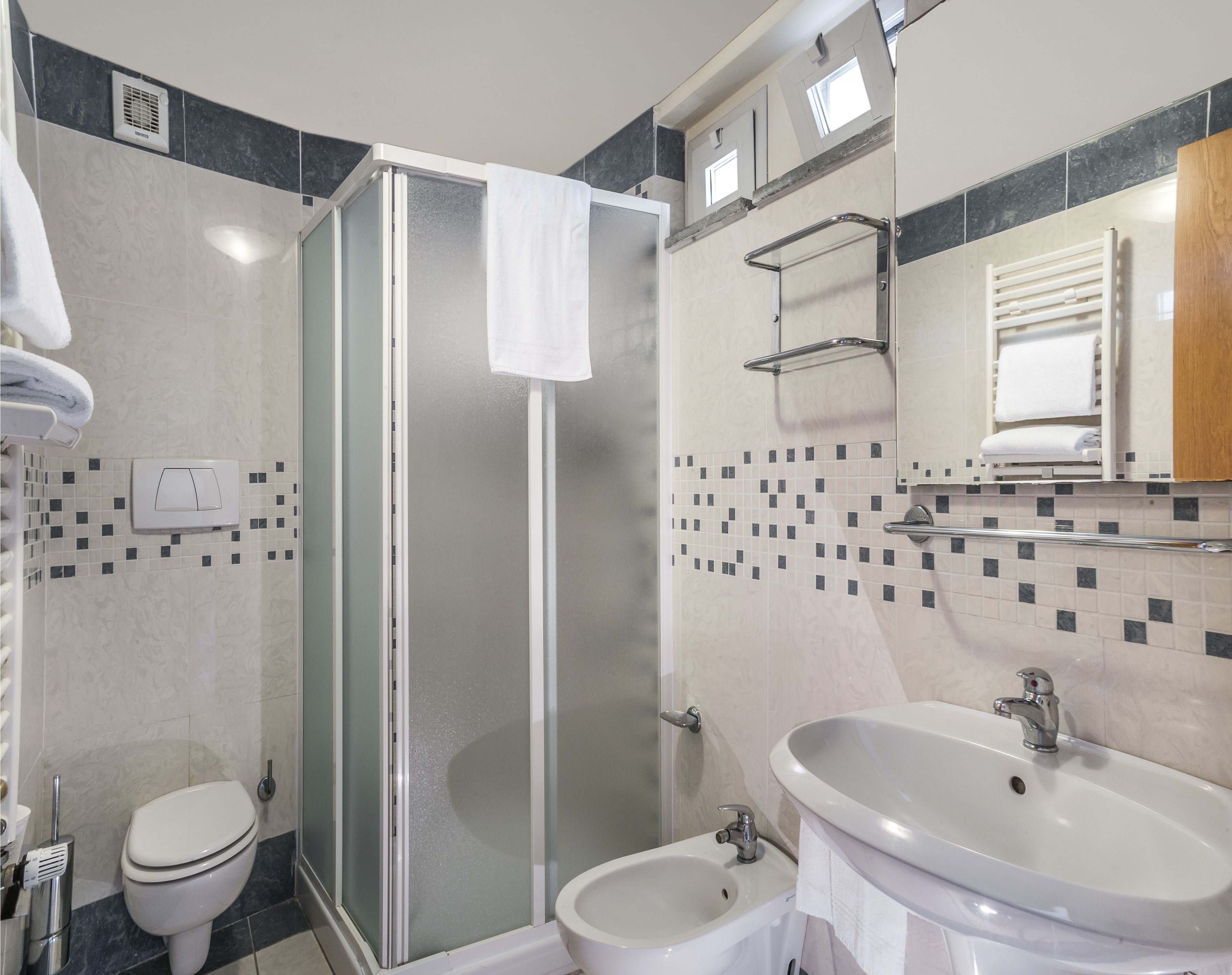 Ein modernes Badezimmer mit einer gläsernen Duschkabine, einer Toilette und einem Waschbecken mit Spiegel darüber.