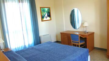 Ein Hotelzimmer mit Bett, Schreibtisch, Stuhl, Spiegel und einem Bild an der Wand.