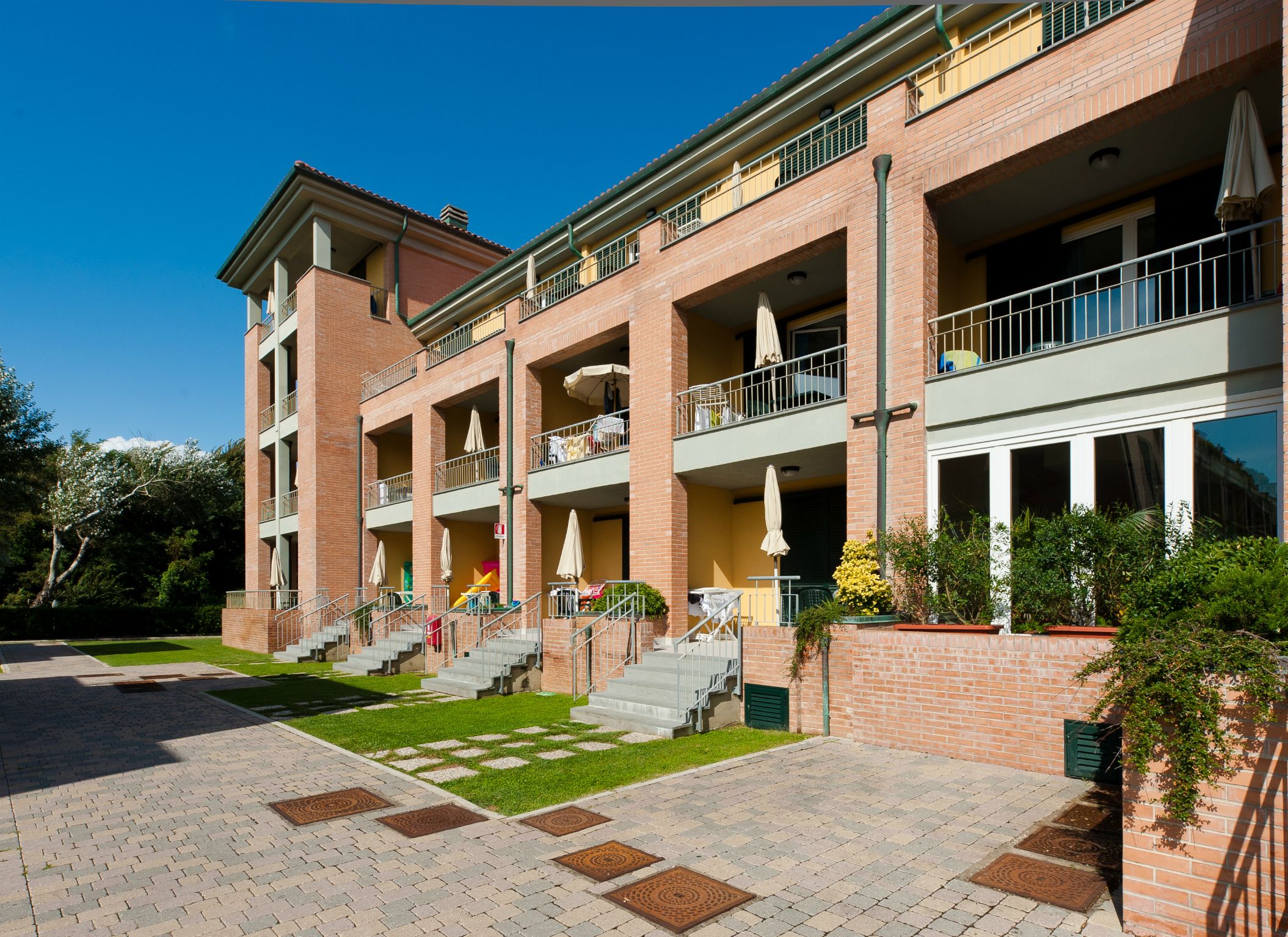 A multi-story hotel with a brick facade, outdoor seating areas, and a well-maintained garden.