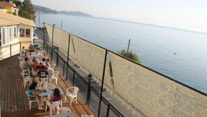 A terrace with outdoor seating overlooking a body of water. - El Greco Hotel by Estia (Corfu)