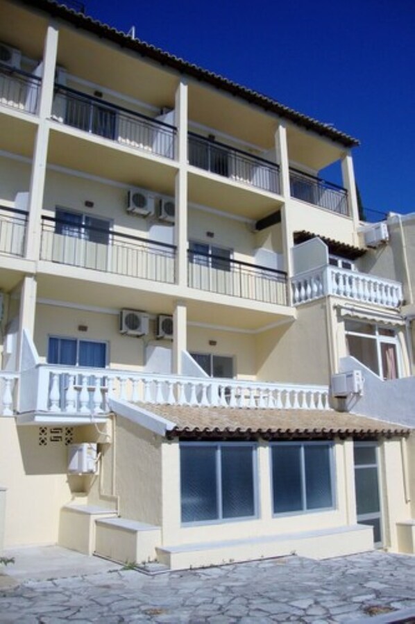 Un edificio de varios pisos con balcones, unidades de aire acondicionado y techo de tejas.