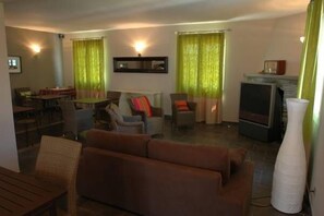 A living room with a sofa, chairs, a TV, and a fireplace. - Hôtel La Palma (Patrimonio)
