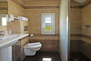 Standaard vierpersoonskamer | Badkamer | Een douche, gratis toiletartikelen, een haardroger, handdoeken