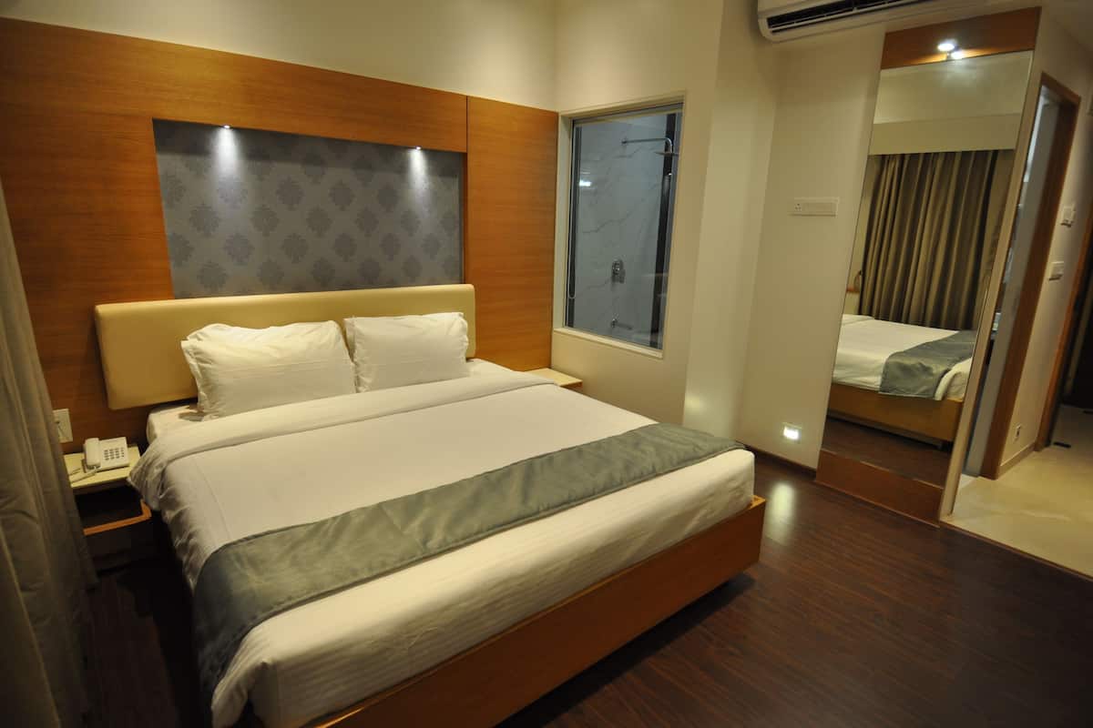A hotel room with a large bed, a bedside telephone, and a window with curtains.
