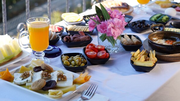 A table set with breakfast items, including fruits, bread, and a glass of orange juice, on a balcony with a view. - Seatanbul Hotel (Istanbul)