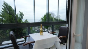A table with a bottle and glasses on a balcony with a view of trees and the sea. - Seatanbul Hotel (Istanbul)