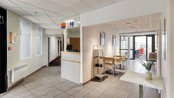 A hotel lobby with a reception desk, seating area, and a view of the outside.