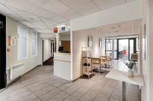 Vestíbulo de hotel con mostrador de recepción, zona de estar y vistas al exterior.