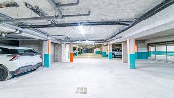 Un parking à plusieurs niveaux, avec des piliers en béton et des tuyaux apparents au plafond.