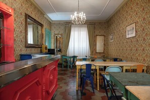 Un espace repas avec un comptoir rouge, plusieurs tables et des chaises.