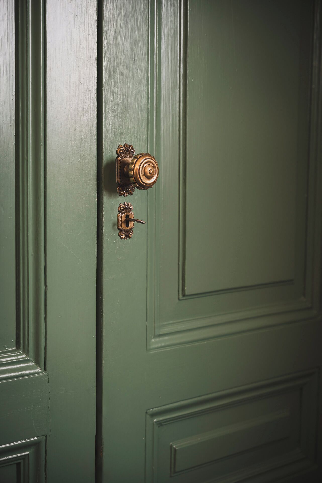 A green door with a brass doorknob and a keyhole.