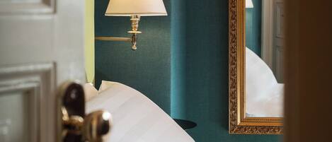 A hotel room with a bed, a nightstand, a lamp, and a mirror.