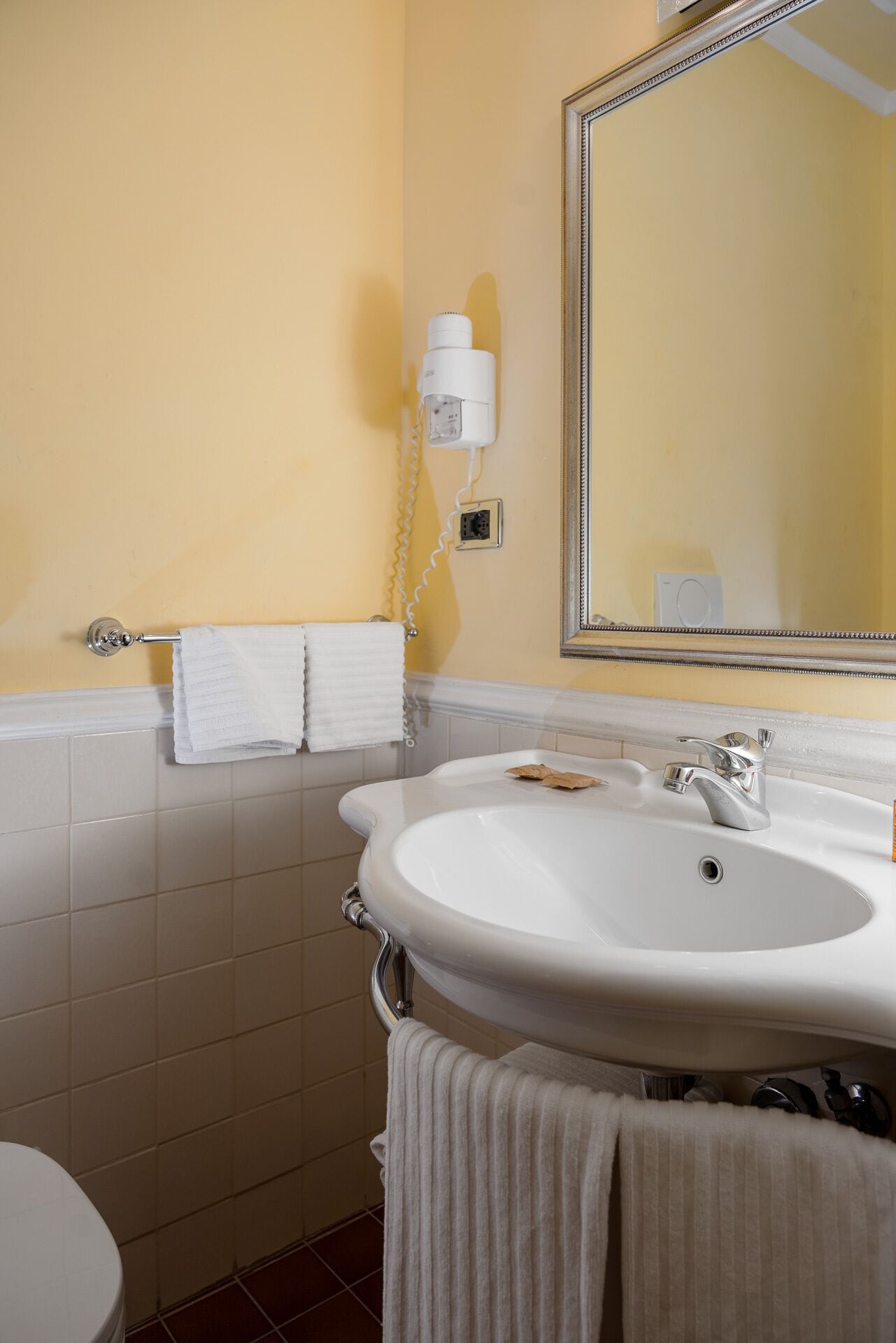Un baño con un lavamanos blanco, un espejo y un toallero.