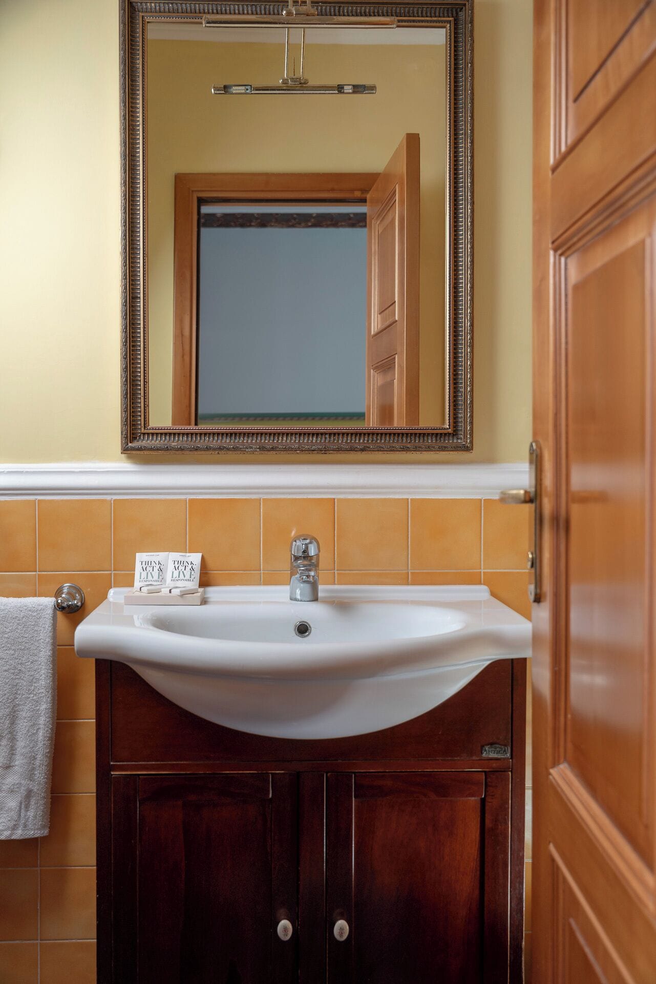 A bathroom with a white sink, a mirror above it, and a towel hanging on the wall.