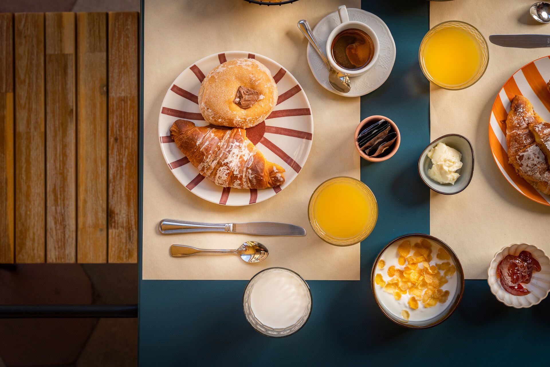 Desayuno con croissants, jugo de naranja, café y diferentes opciones de untar en una mesa.
