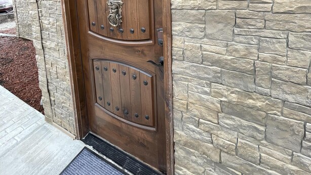 Una puerta de madera con un aldabón decorativo y un farol encima.