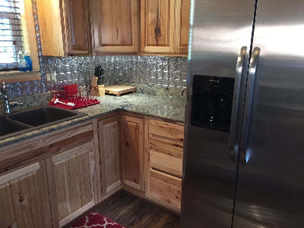 A kitchen with wooden cabinets, a stainless steel refrigerator, and a granite countertop.