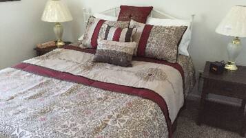 A neatly made bed with patterned bedding and pillows, two bedside lamps, and a small bedside table with a lamp.