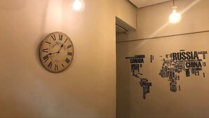 A wall clock with Roman numerals and a world map made of country names. - Hostal MYD Los Perales (Madrid)