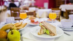 Ein Frühstückstisch mit einem Sandwich, Obst und Orangensaft.