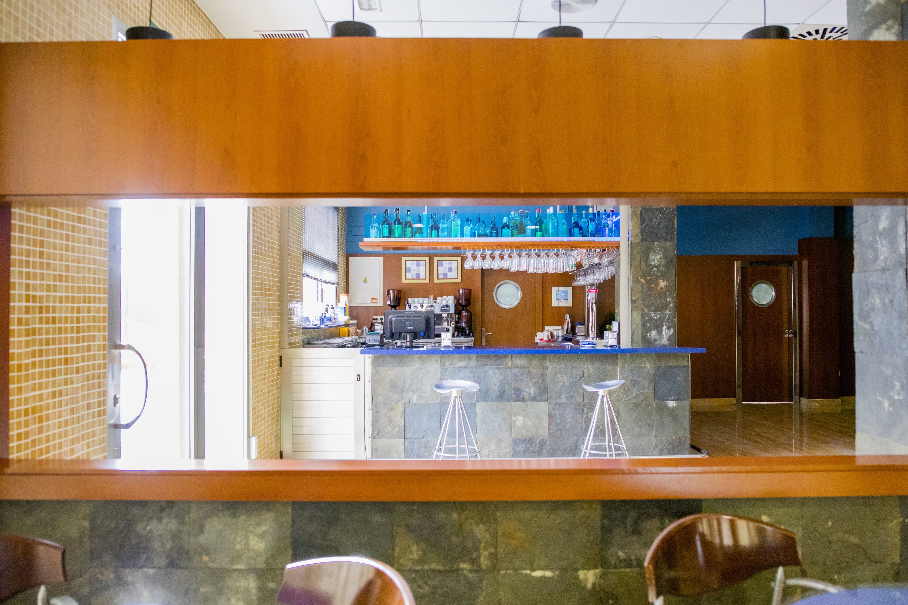 Een bar met een toonbank, barkrukken en een presentatie van flessen.