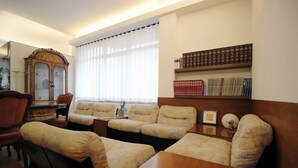A living room with a wooden coffee table, two sofas, a wooden cabinet, and a bookshelf with books.