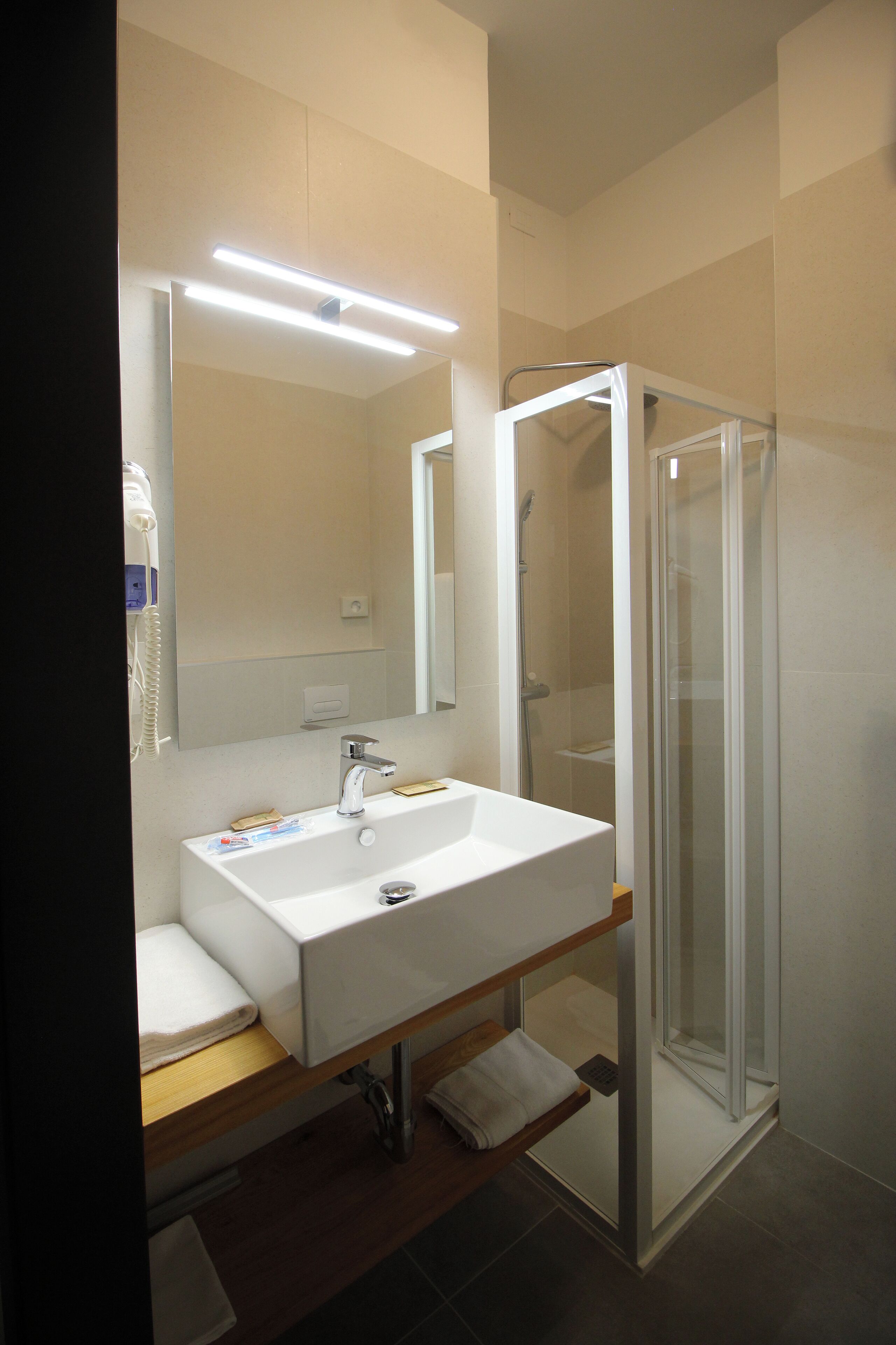 Une salle de bain moderne avec un lavabo blanc, un miroir et une cabine de douche en verre.