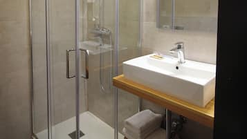 A modern bathroom with a glass-enclosed shower, a white sink, and a mirror above it.