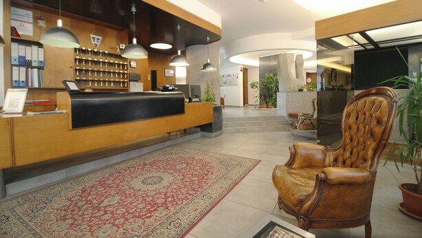 A reception area with a wooden desk, a leather chair, and a patterned rug.