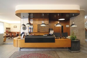 A reception area with a curved desk, multiple pendant lights, a clock, and a plant.