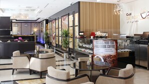 L’intérieur d’un café moderne, avec des tables et des chaises, un appareil à café et un panneau indiquant les raisons de boire du café.
