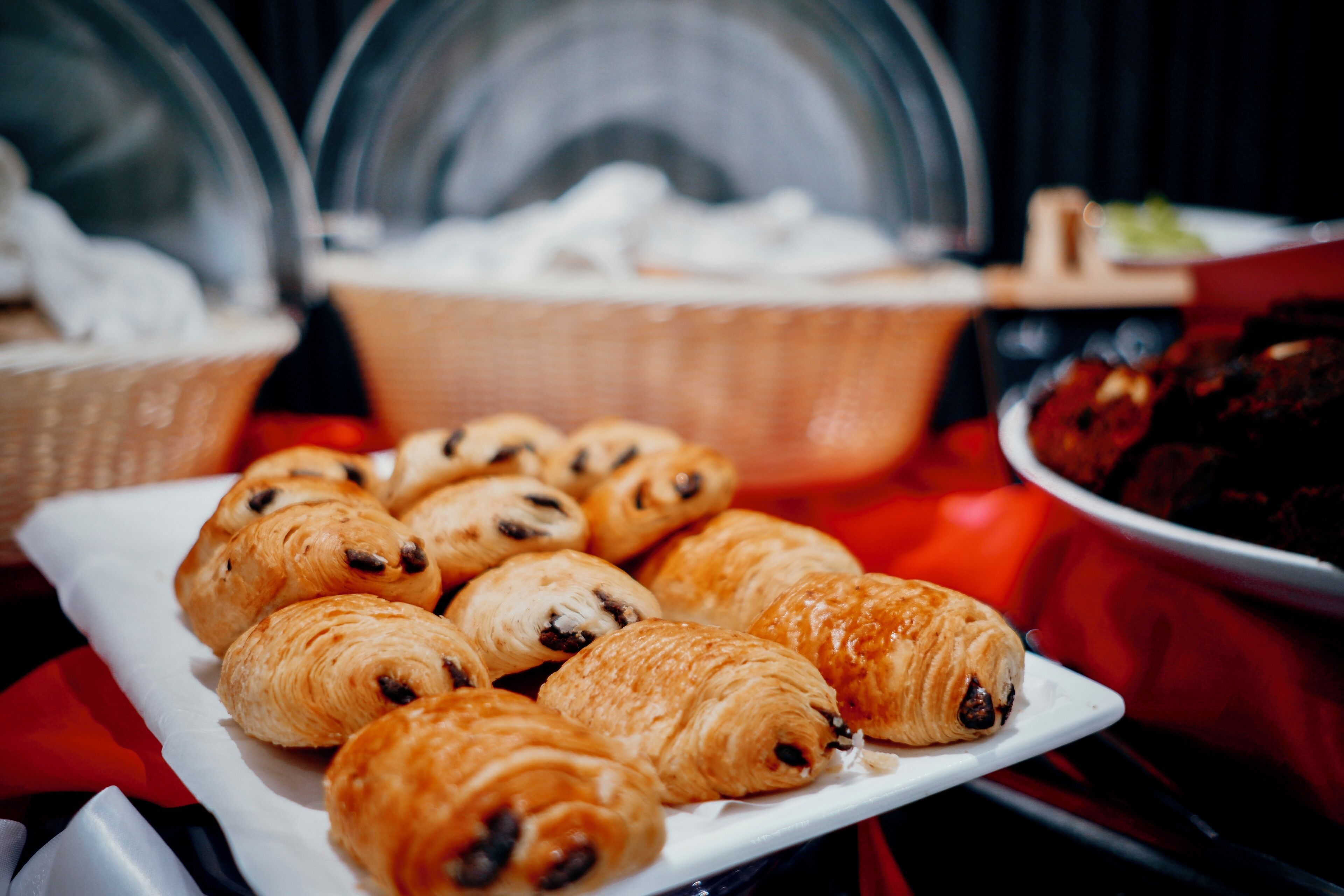 A plate of croissants on a table with a red cloth.