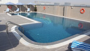 Une piscine avec des chaises longues rayées de bleu et de blanc, une bouée de sauvetage et une échelle en métal.