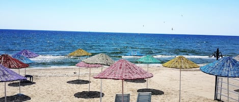 Aan een privéstrand, ligstoelen, parasols, beachvolleybal
