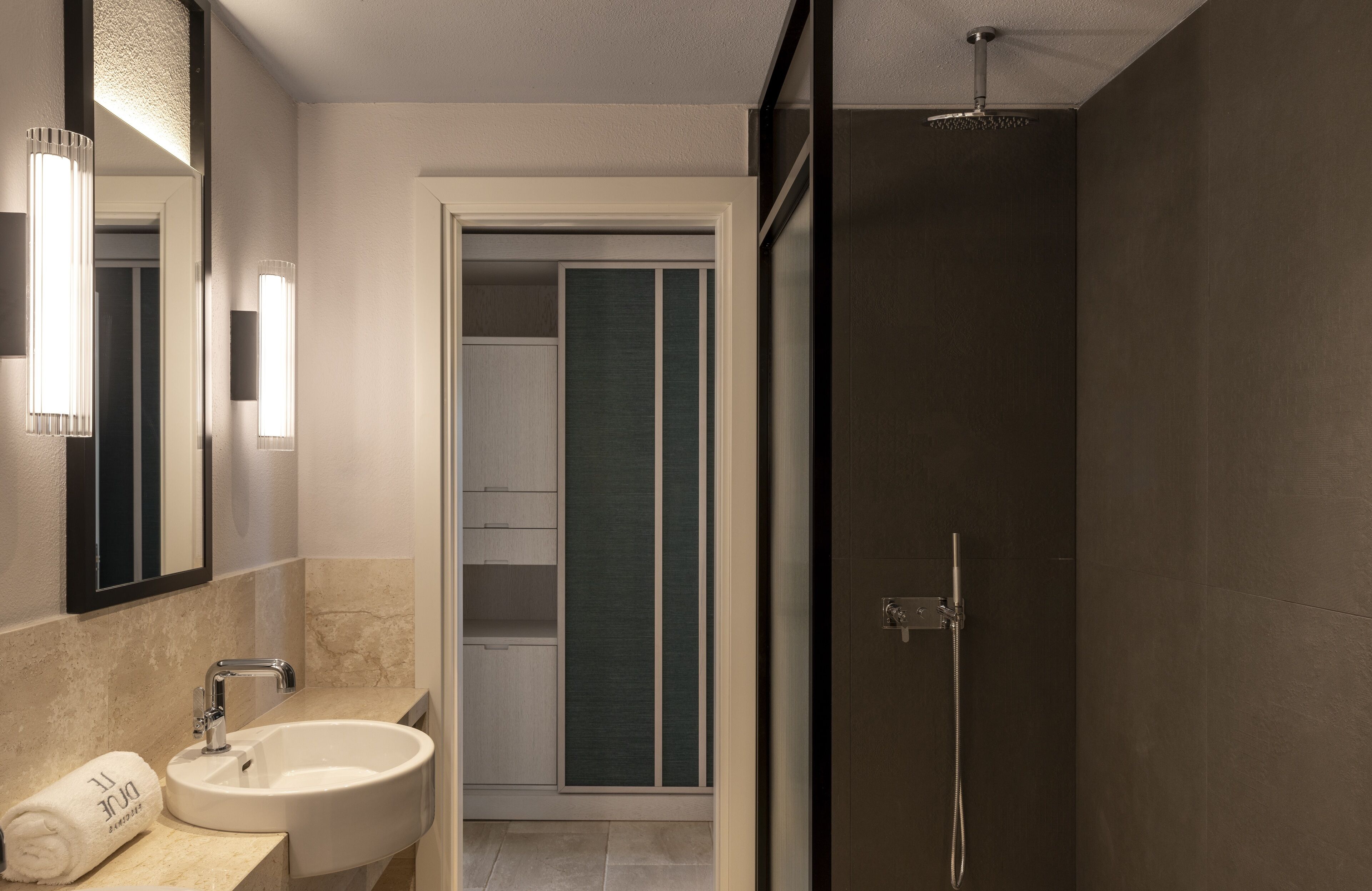 A modern bathroom with a sink, mirror, and shower.