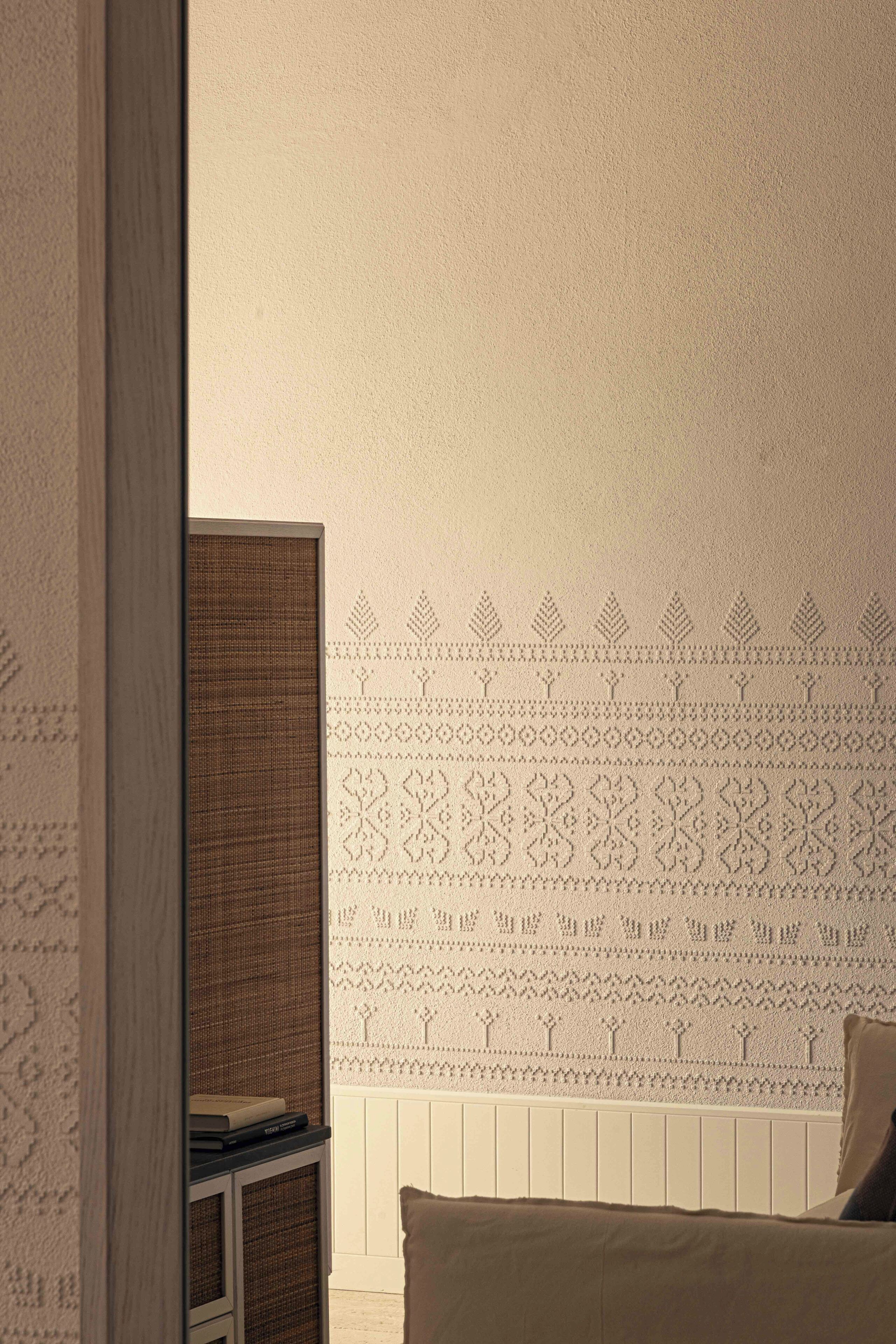 Une chambre à coucher avec un lit, une armoire et un mur décoré d’un motif.