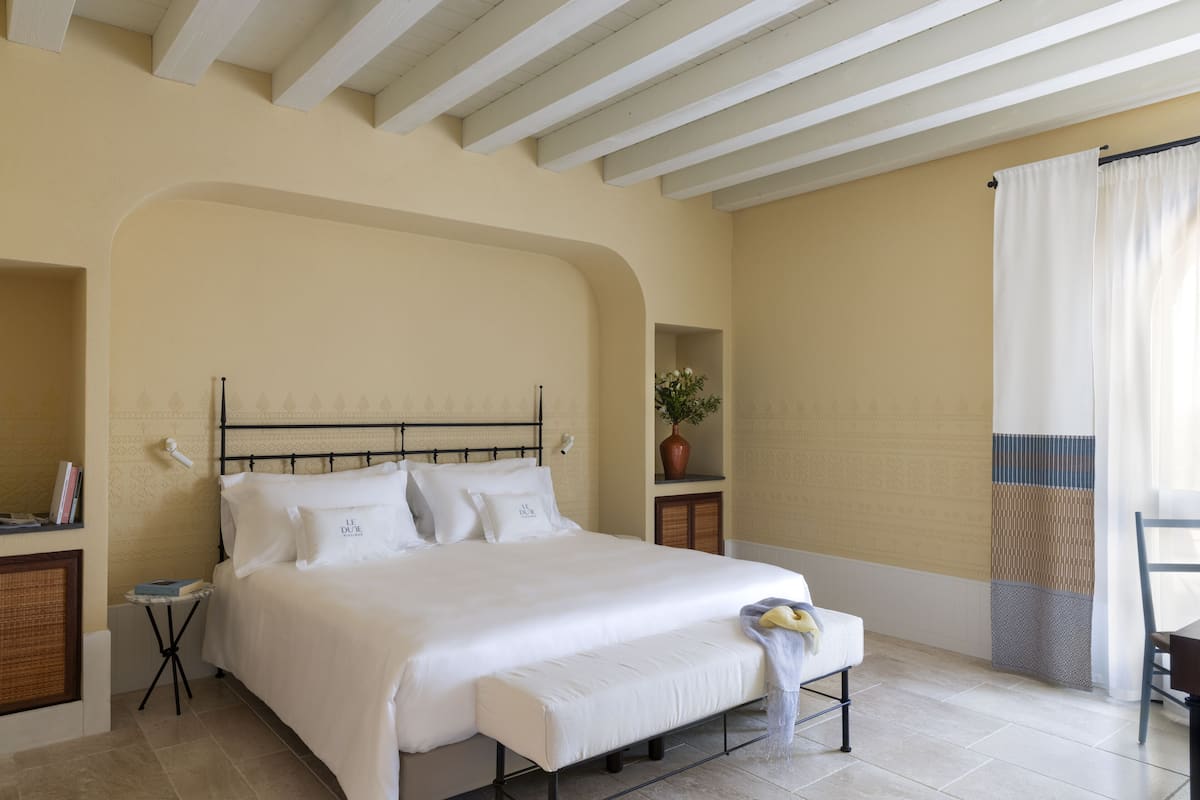 A bedroom with a bed, bedside tables, a potted plant, and a window with curtains.