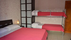 A room with two beds, each with a red bedspread and white pillows. There is a nightstand with a lamp between the beds. - Sa Marina (Siniscola)