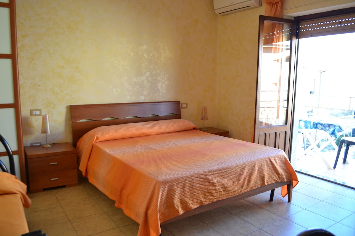 Une chambre à coucher avec un lit, une table de chevet et une vue sur l’extérieur.