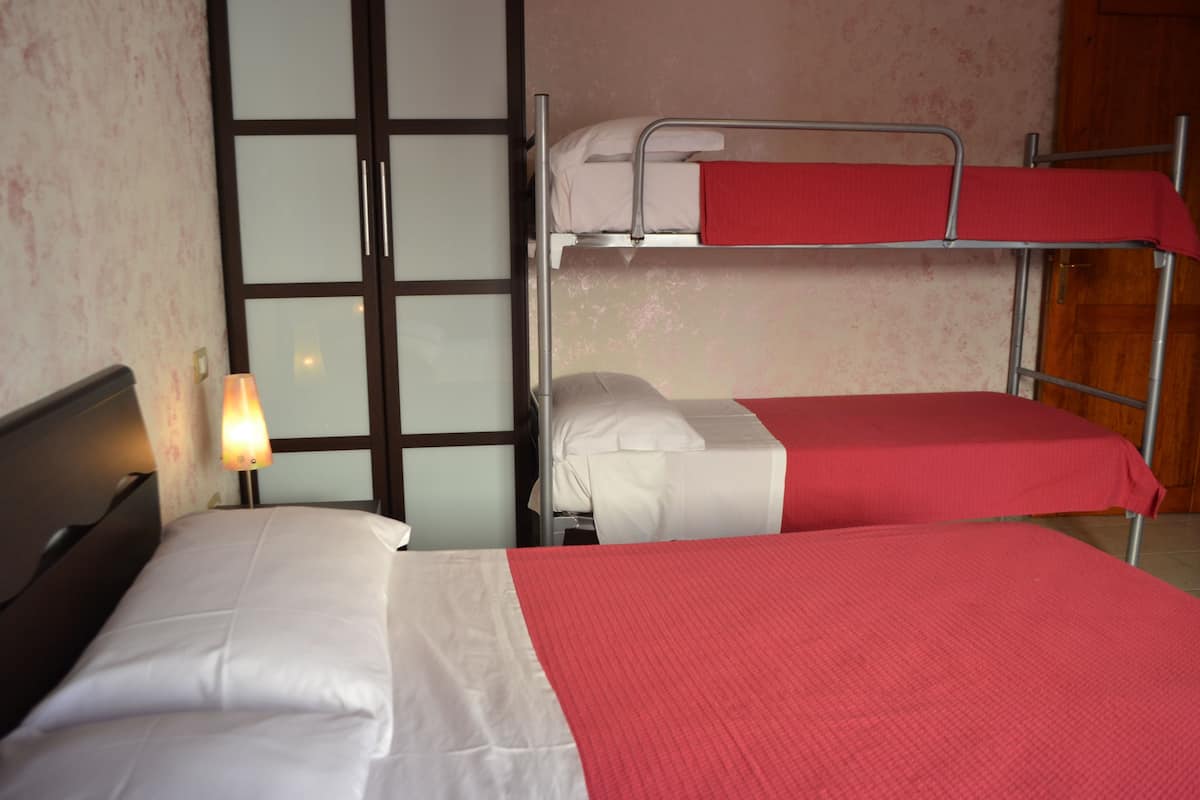 Une chambre avec un lit simple et deux lits superposés.