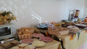 A buffet table with various food items including bread, pastries, and meats. - Sa Marina (Siniscola)