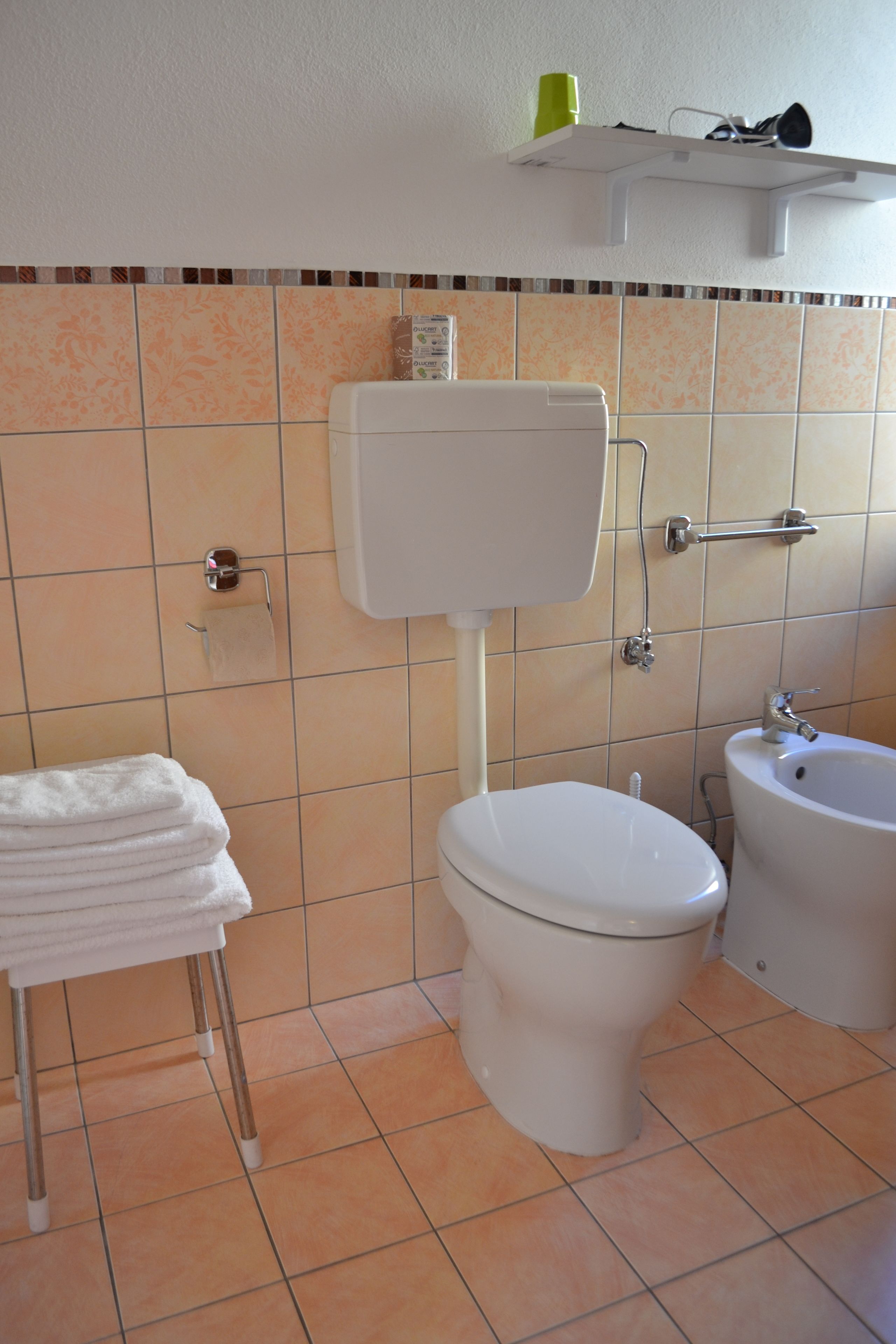 Un baño con inodoro, bidé y un perchero para toallas.