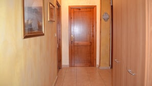 A hallway with wooden doors, a framed picture on the left, and a door number sign on the right. - Sa Marina (Siniscola)